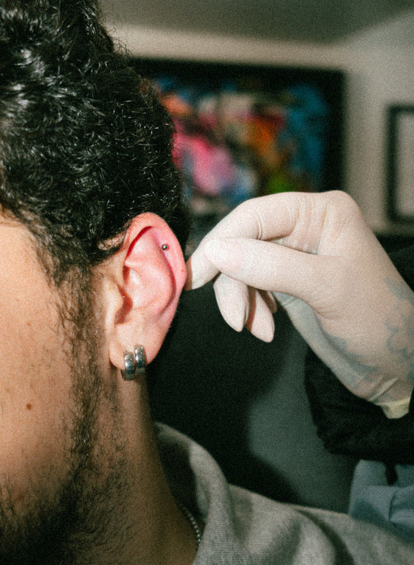 Piercer checking a client's healing ear piercing